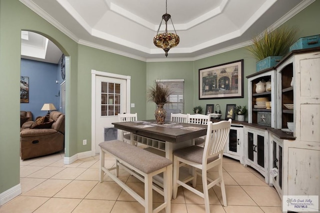 tiled dining space with a tray ceiling and crown molding