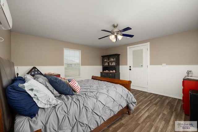 bedroom with ceiling fan, dark wood-type flooring, and a wall unit AC