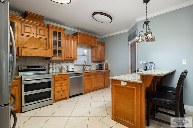 kitchen with decorative backsplash, ornamental molding, stainless steel appliances, hanging light fixtures, and a breakfast bar area