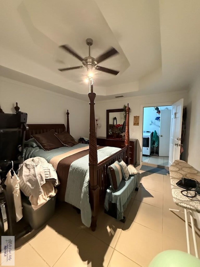 bedroom with a raised ceiling, ceiling fan, and light tile patterned flooring