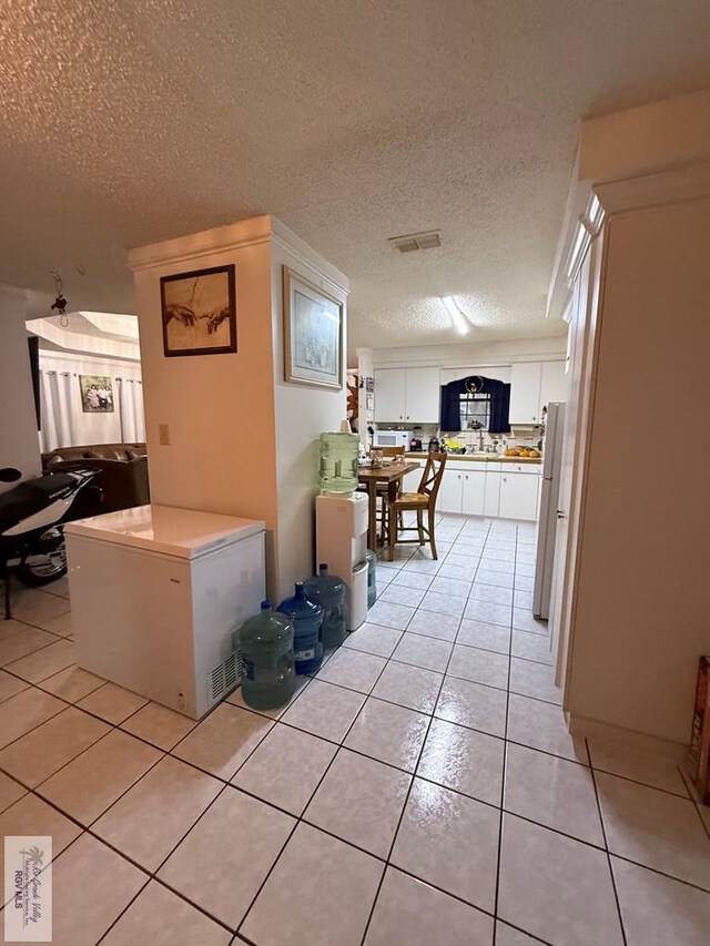 corridor with sink, light tile patterned floors, and a textured ceiling