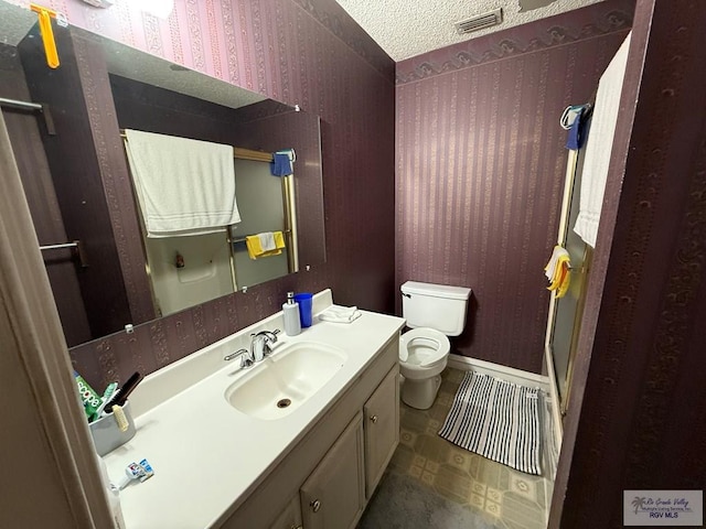 bathroom featuring a textured ceiling, vanity, and toilet