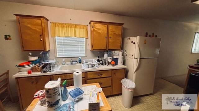 1330 Reagan St Unit 3, San Benito, TX 78586 - kitchen with a sink, brown cabinetry, light countertops, and freestanding refrigerator