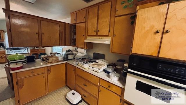 1330 Reagan St Unit 3, San Benito, TX 78586 - kitchen with brown cabinets, under cabinet range hood, oven, and light countertops
