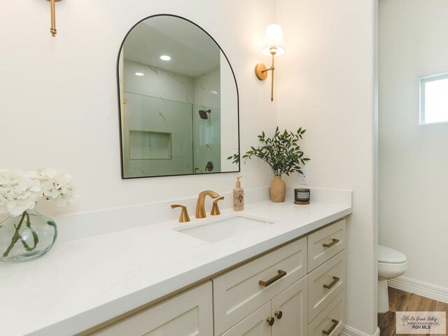 23100 Hidalgo Ave, Harlingen, TX 78552 - full bathroom with vanity, toilet, a marble finish shower, and wood finished floors