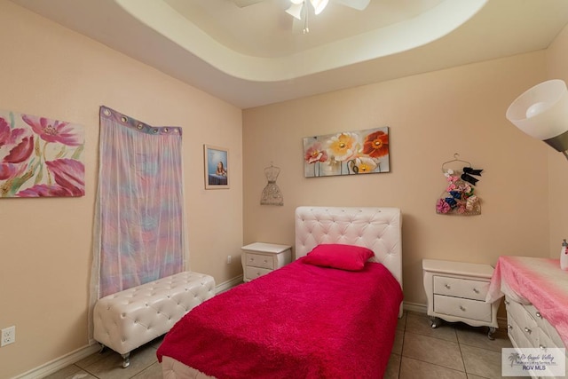 bedroom featuring ceiling fan, light tile patterned floors, and a tray ceiling