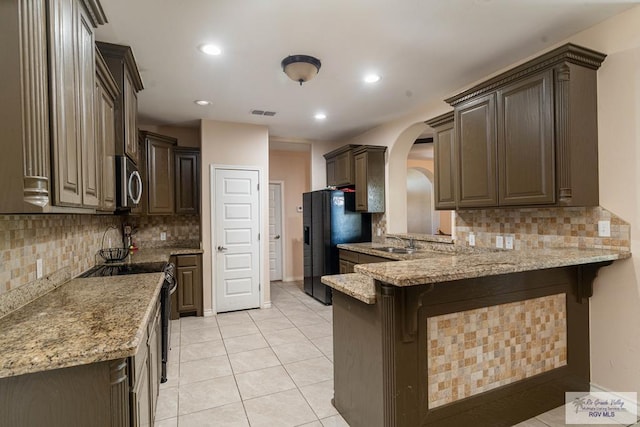 kitchen with sink, tasteful backsplash, light stone counters, kitchen peninsula, and stainless steel appliances