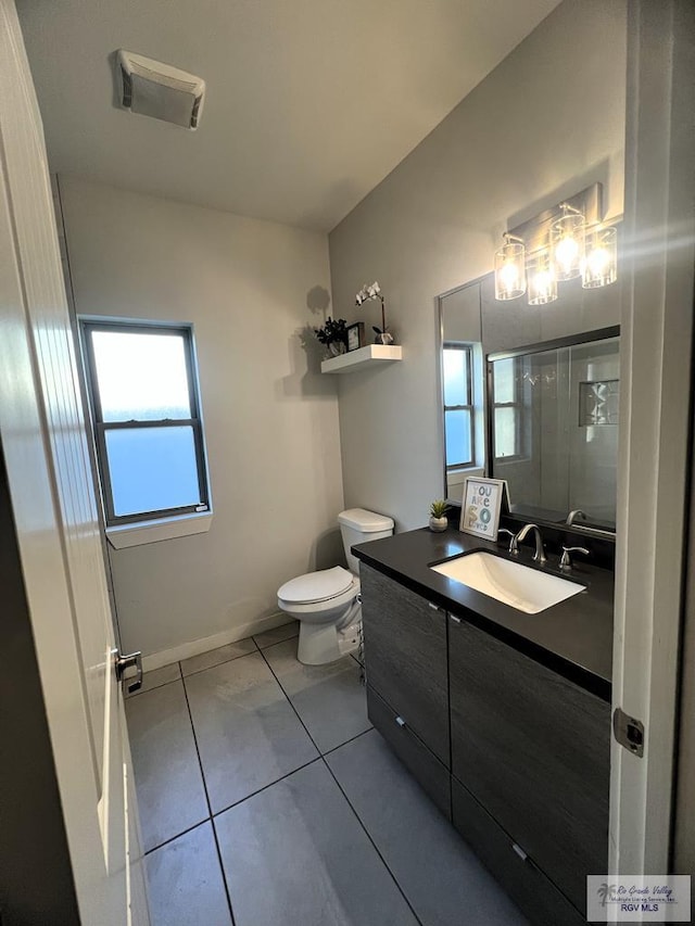 bathroom with tile patterned floors, vanity, toilet, and a shower with shower door