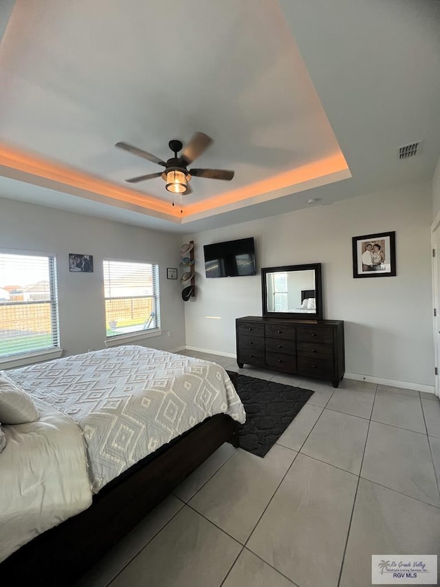 tiled bedroom with ceiling fan and a raised ceiling