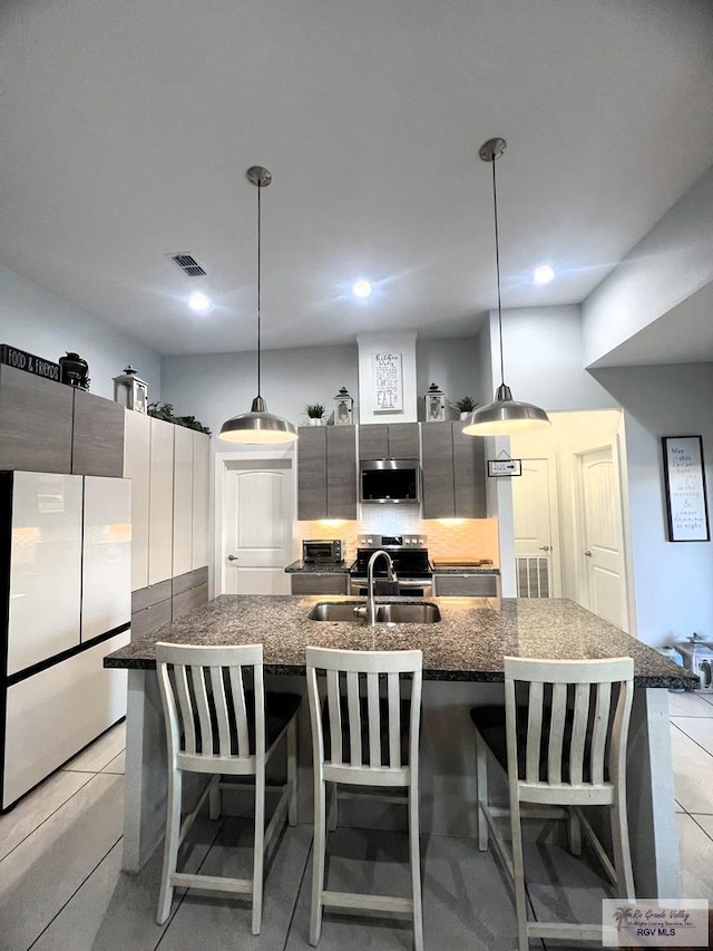 kitchen with a kitchen bar, stainless steel appliances, and hanging light fixtures