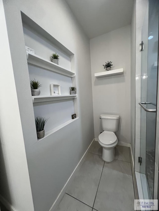 bathroom with tile patterned flooring, toilet, and a shower with shower door