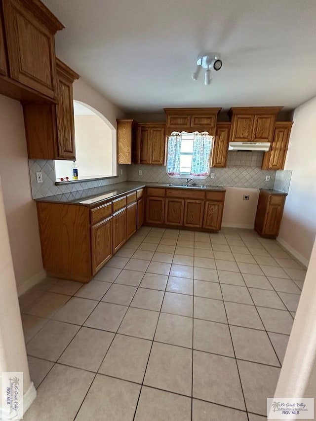 kitchen with brown cabinetry, backsplash, and a sink