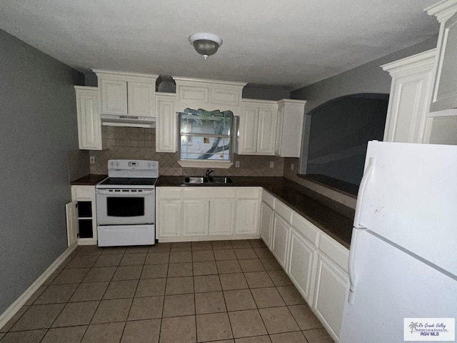 kitchen with dark countertops, tasteful backsplash, a sink, white appliances, and under cabinet range hood