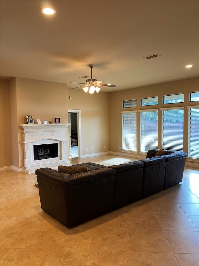 tiled living room with a high end fireplace and ceiling fan