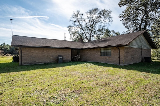 rear view of property with central AC and a lawn