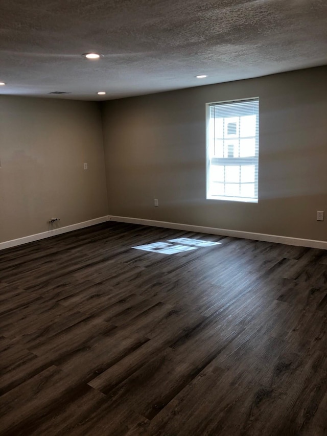 spare room featuring dark wood-type flooring and a textured ceiling