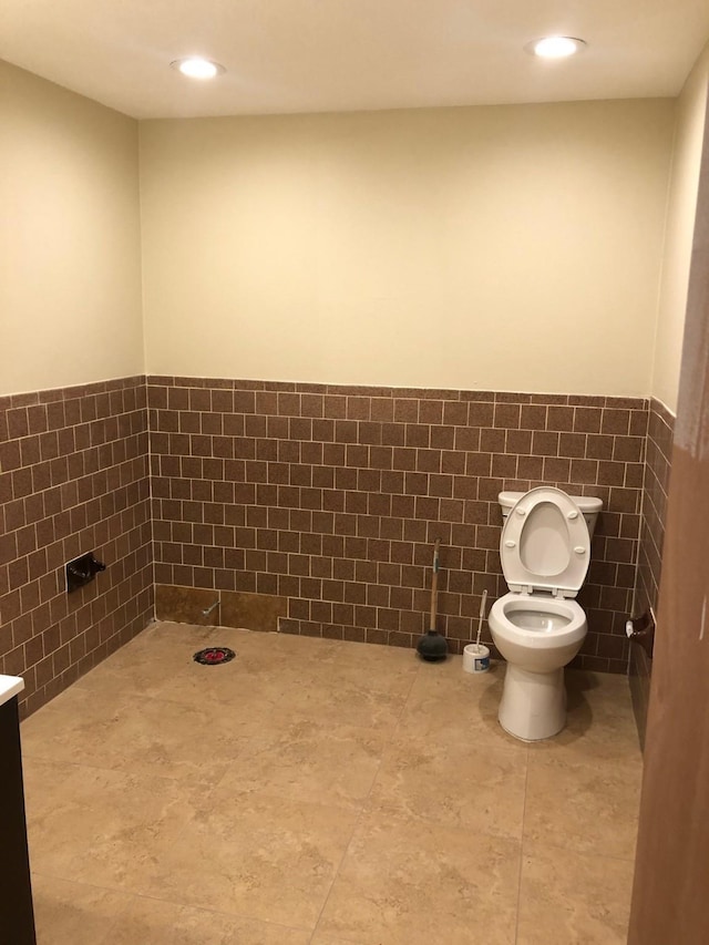 bathroom with tile walls, tile floors, toilet, and vanity