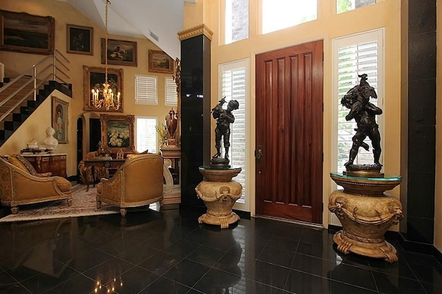 entrance foyer featuring dark tile patterned floors and high vaulted ceiling