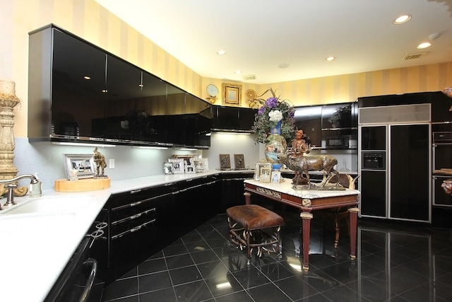 kitchen featuring dishwasher, paneled fridge, dark tile patterned floors, and sink