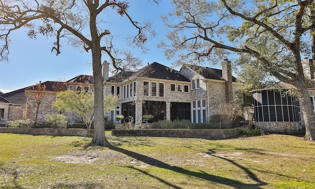 rear view of house with a sunroom and a lawn