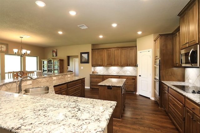 kitchen with an island with sink, stainless steel appliances, tasteful backsplash, and hanging light fixtures