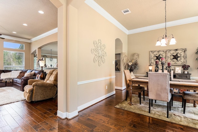 dining space with crown molding, dark hardwood / wood-style floors, and an inviting chandelier