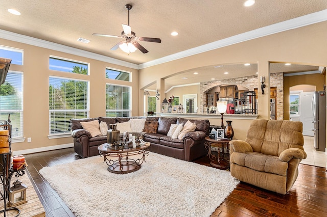 living room featuring crown molding, ceiling fan, a textured ceiling, and dark hardwood / wood-style flooring