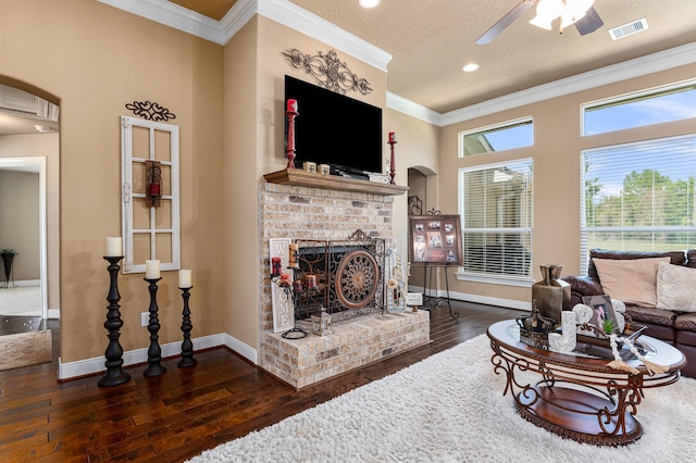 living room with crown molding, dark wood-type flooring, a brick fireplace, and a textured ceiling