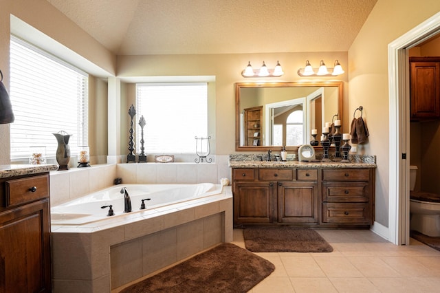 bathroom with toilet, tiled tub, tile flooring, a textured ceiling, and vanity