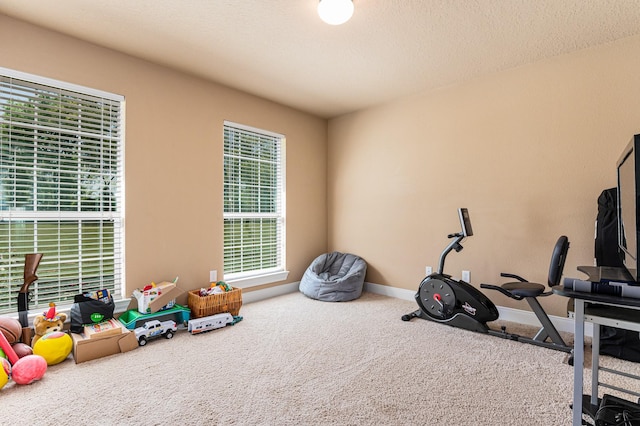 workout area featuring a textured ceiling and carpet flooring