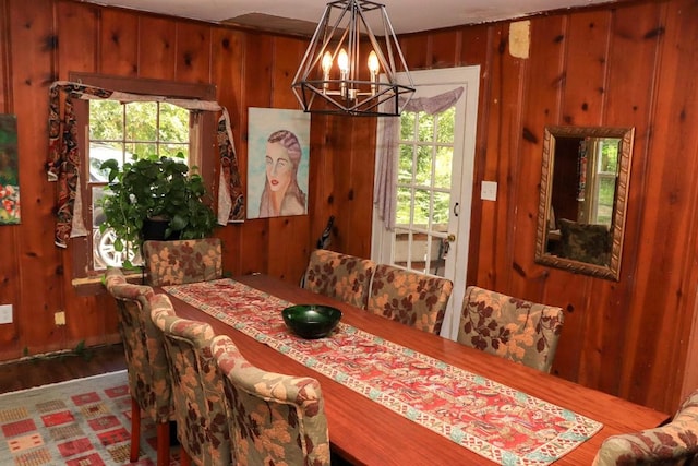 dining room featuring wooden walls, plenty of natural light, and an inviting chandelier