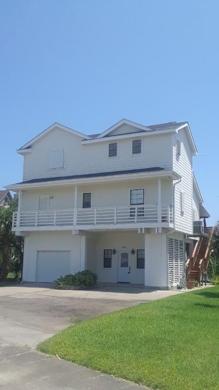 exterior space featuring central AC unit, a yard, a balcony, and a garage