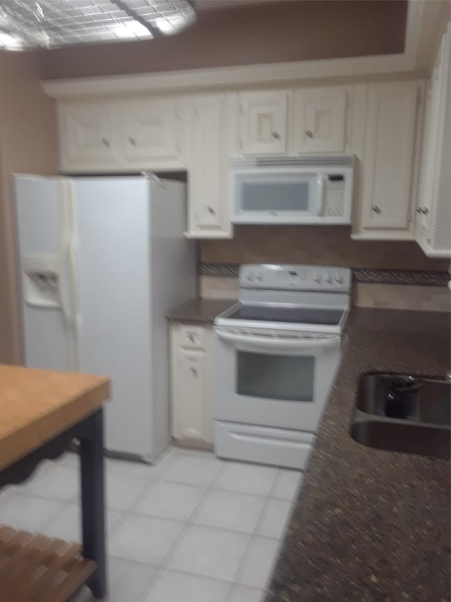 kitchen with white appliances, white cabinets, and light tile floors