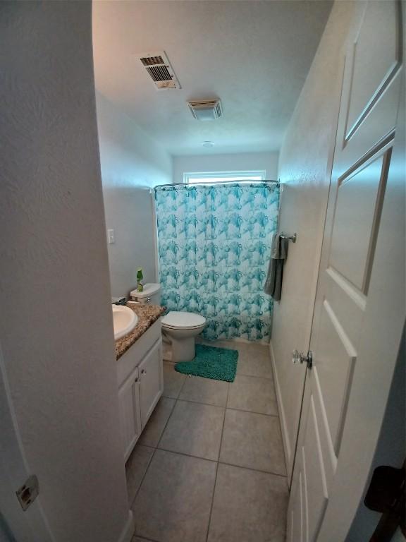 bathroom featuring toilet, vanity, and tile flooring