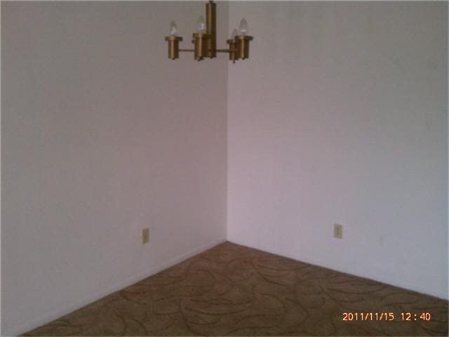 spare room featuring an inviting chandelier and carpet