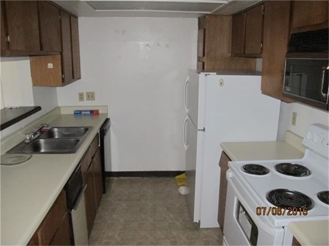 kitchen featuring dishwashing machine, sink, light tile floors, and electric range