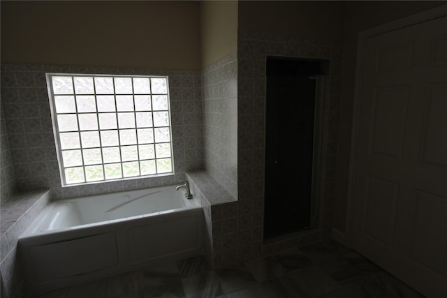 bathroom with tile floors, separate shower and tub, and tile walls