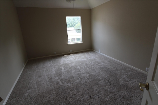 unfurnished room with lofted ceiling and dark colored carpet