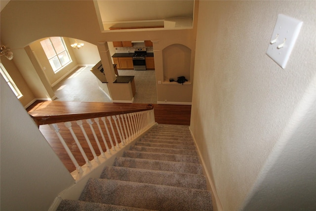 stairway with light wood-type flooring, a chandelier, and a high ceiling