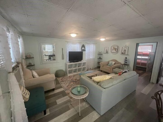 living room with a drop ceiling, dark hardwood / wood-style floors, and a wealth of natural light