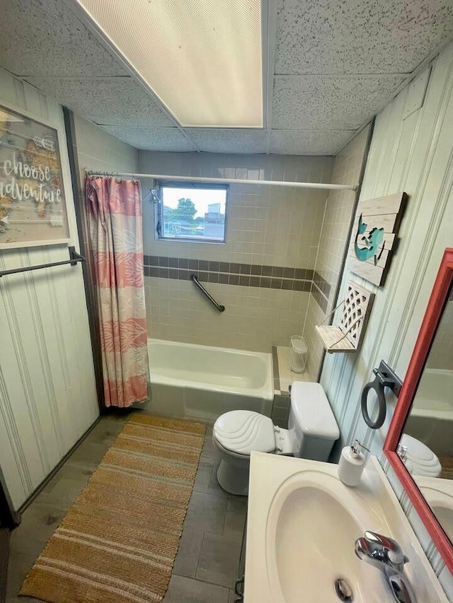 full bathroom with tile floors, sink, shower / bathtub combination with curtain, toilet, and a drop ceiling