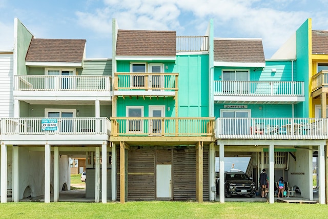 rear view of property featuring a lawn and a balcony