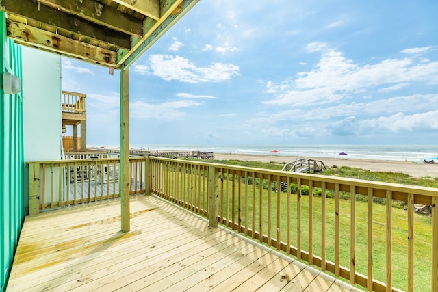 deck with a lawn, a water view, and a beach view