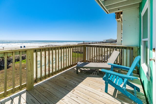 wooden deck featuring a water view and a view of the beach