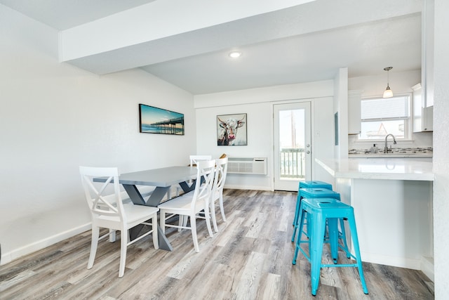 dining area featuring a wall mounted air conditioner, light hardwood / wood-style flooring, and sink