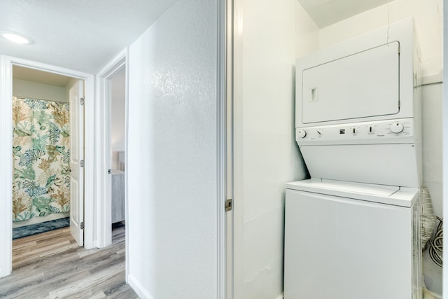 laundry area with stacked washer / dryer and light wood-type flooring