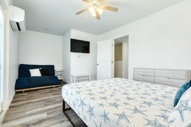 bedroom with light hardwood / wood-style floors, ceiling fan, and a wall mounted AC