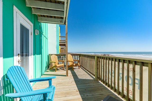 wooden terrace with a water view and a view of the beach