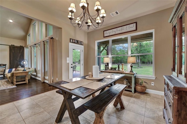 tiled dining room featuring a barn door, lofted ceiling, a chandelier, and a wealth of natural light