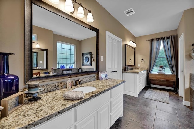 bathroom featuring tile flooring, double vanity, and a healthy amount of sunlight